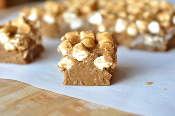 Marshmallow topped light colored squares of fudge on a piece of parchment paper.
