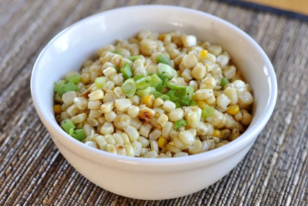 White bowl with grilled corn kernels and topped with green onion.