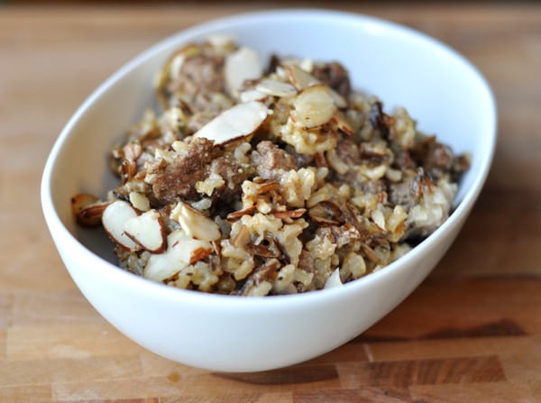 Oval white bowl with cooked wild rice topped with sliced almonds.