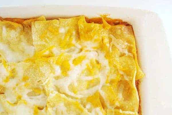 White casserole dish with tortilla casserole and melted cheese.