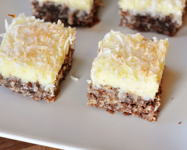 Top view of coconut-topped cream cheese haystack squares on a white platter.