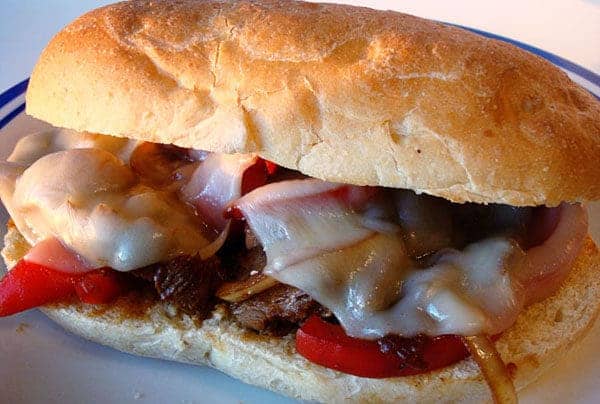 Hoagie with steak, onions, melted cheese, and peppers.