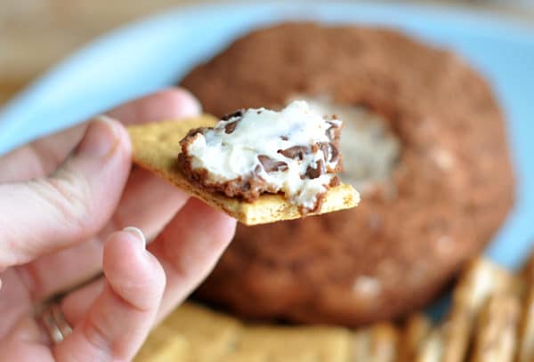 Cocoa dusted cheeseball with a bite taken out on a graham cracker.