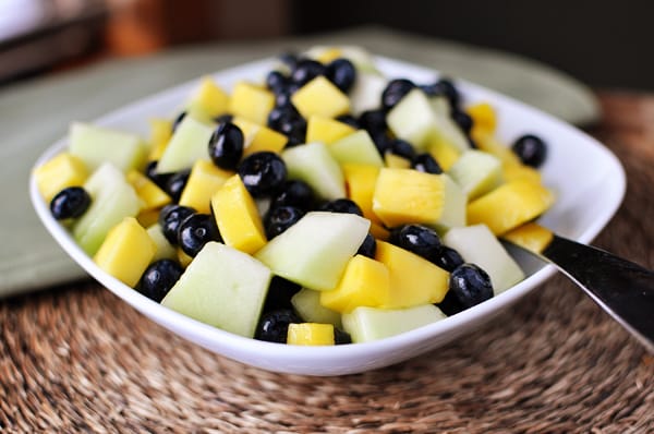 White bowl with a honeydew, mango and blueberry salad.