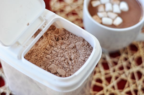 white tupperware container with the lid open showing powdered hot chocolate mix