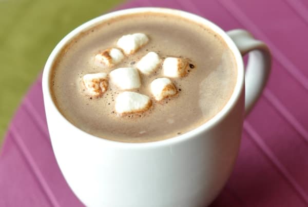 White mug filled with hot chocolate with marshmallows floating on top.