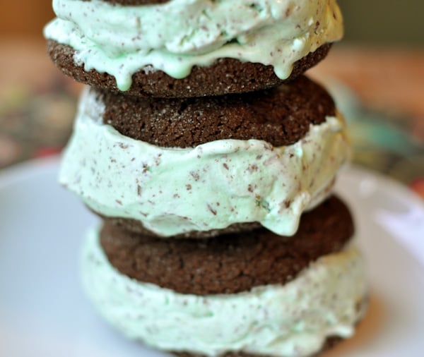 Side view of stacked chocolate mint chip ice cream sandwiches on a white plate.