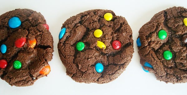 Three chocolate m&m cookies lined up in a row.