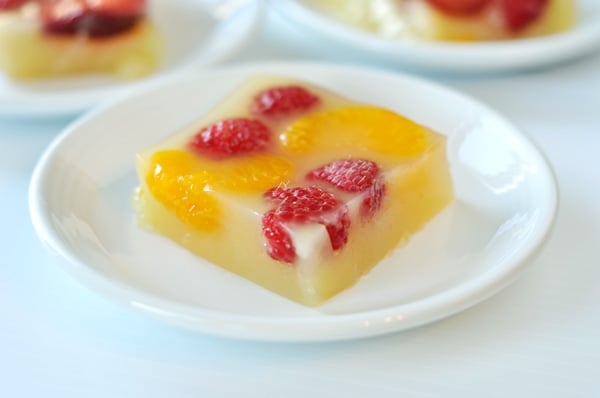 White plate with a piece of raspberry and mandarin orange jello.