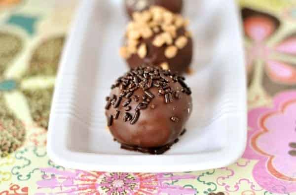 Chocolate-dipped bonbons on a white rectangular dish.