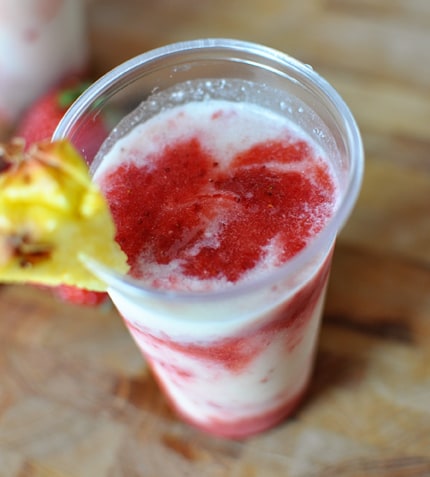 Top view of a strawberry and coconut swirled drink in a clear plastic cup.
