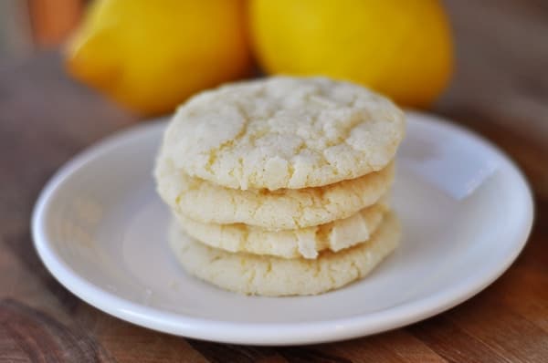 White plate with four lemon cookies stacked on top of each other.