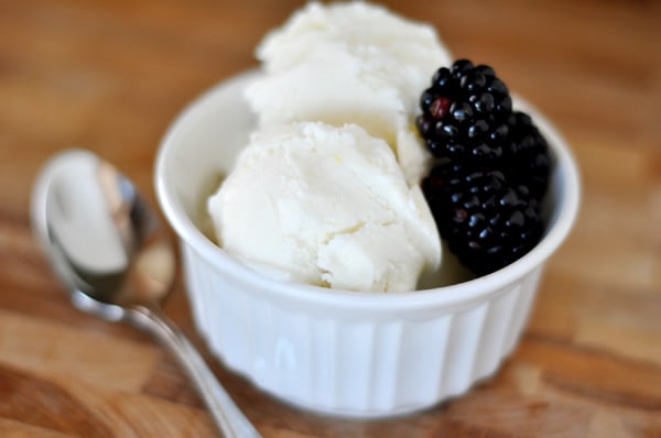 white ramekin with two scoops of lemon ice cream and fresh blackberries on the side