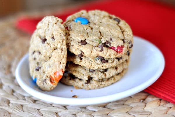 A stack of M&M chocolate chip oat cookies on a white plate.