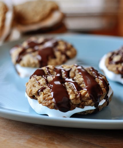 Chocolate drizzled oatmeal cream pies on a blue plate.