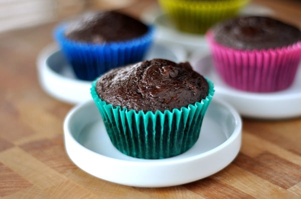 Chocolate muffins in colorful liners on small white plates.