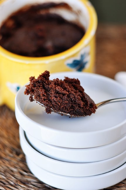 A spoonful of chocolate mug cake on a stack of white plates.