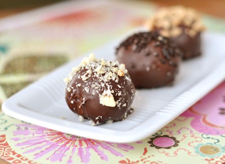 Chocolate-dipped bonbons in a row on a white rectangular platter.