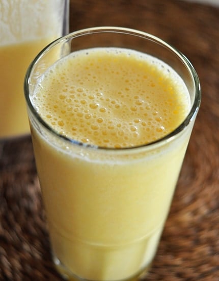 A tall glass cup filled with an orange julius drink.