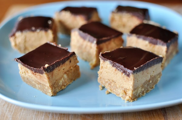 Blue plate with three-layer chocolate peanut butter bars cut into squares.