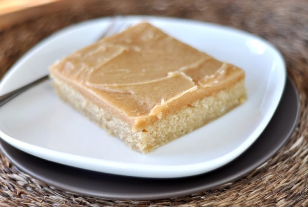 A piece of frosted peanut butter sheet cake on a white plate.