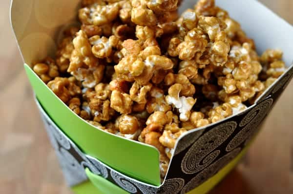 A decorative green container filled with toffee popcorn.