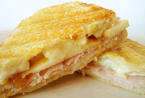 Panini cut in half with melted brie and turkey.