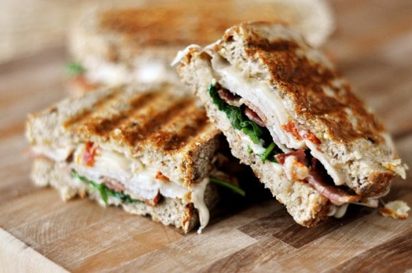 A turkey club panini cut in half on a wooden countertop.