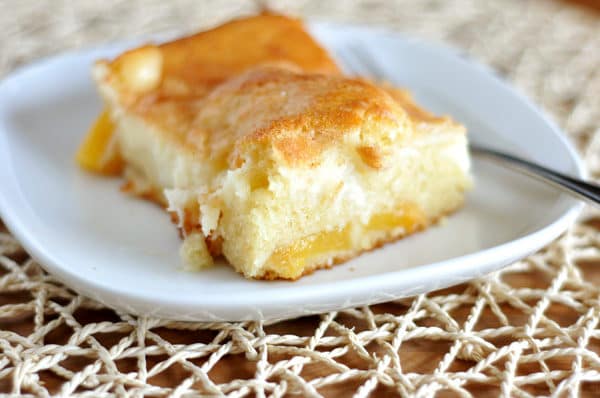 A slice of peaches and cream cake on a white plate.