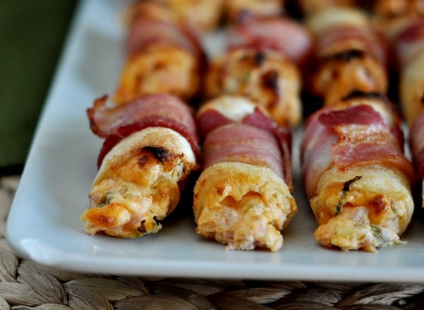 Bacon wrapped cheese bites on a white plate.