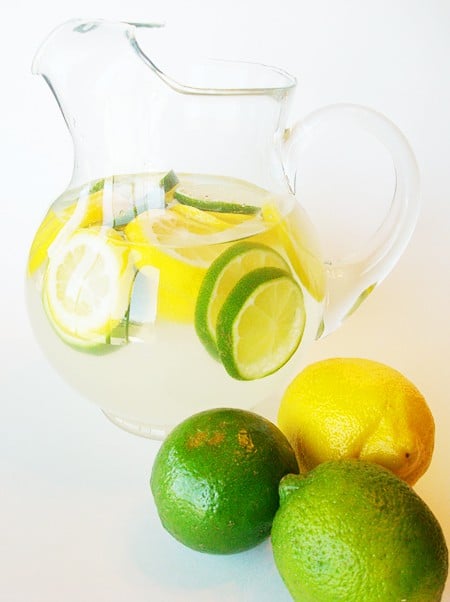 Glass pitcher with clear punch and lemon and lime slices.