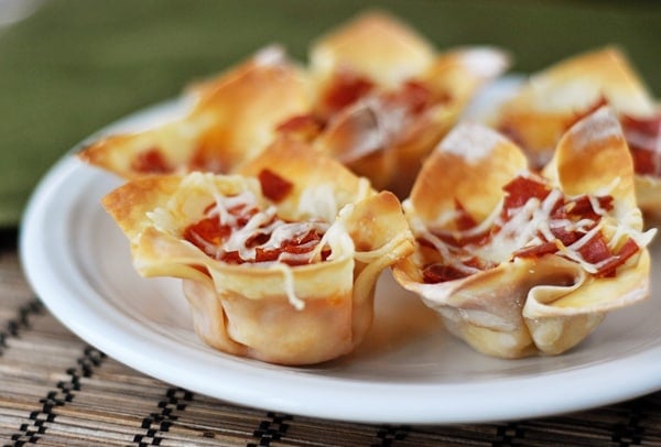 Pizza appetizers cooked in wonton wrappers on a white plate.