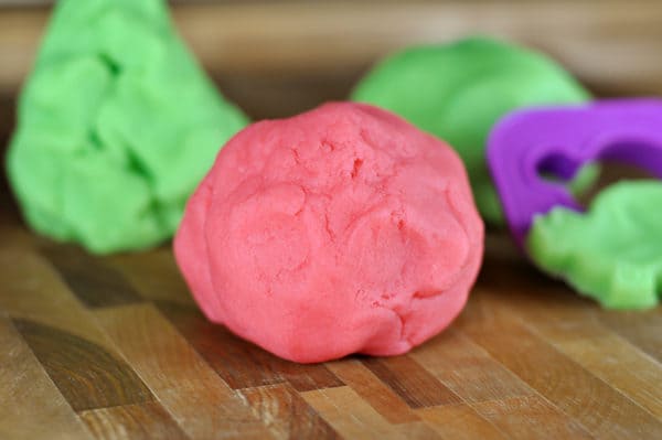 Pink and green playdough on wooden counter.