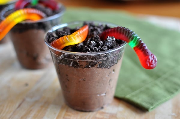 Oreo dirt pudding in clear plastic cups with a gummy worm sticking out of each cup.