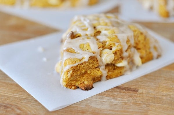 A glazed pumpkin scone on a piece of parchment paper.