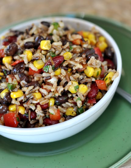 White bowl full of confetti rice salad with corn, peppers, and black beans.