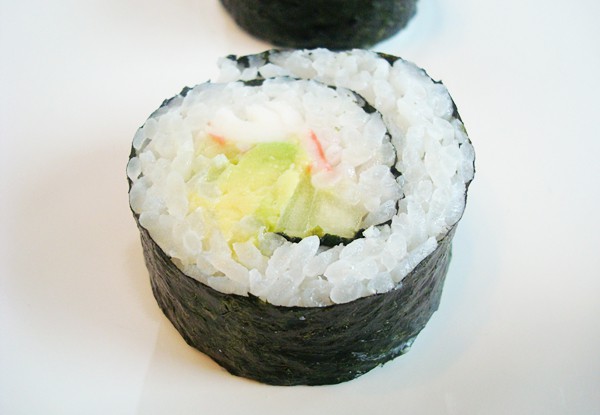 Top view of a California sushi roll on a white plate.