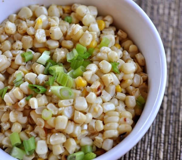 White bowl with grilled corn kernels and chopped green onions.