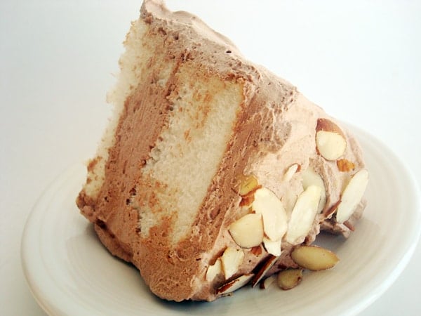 Slice of angel food cake with chocolate frosting on a white plate.