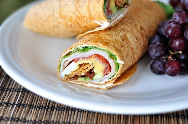 Inside view of a smoked turkey cobb wrap cut in half on a white plate.