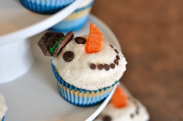 Cupcakes decorated like snowmen on a cupcake tier.