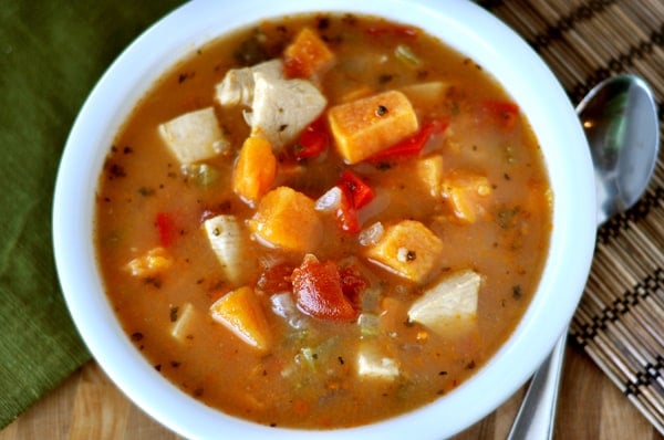 Top view of a white bowl full of chicken and sweet potato soup.