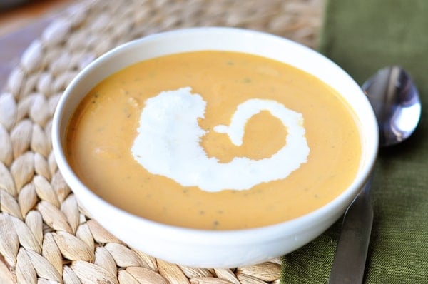 White bowl of tomato soup with cream swirled in the middle.