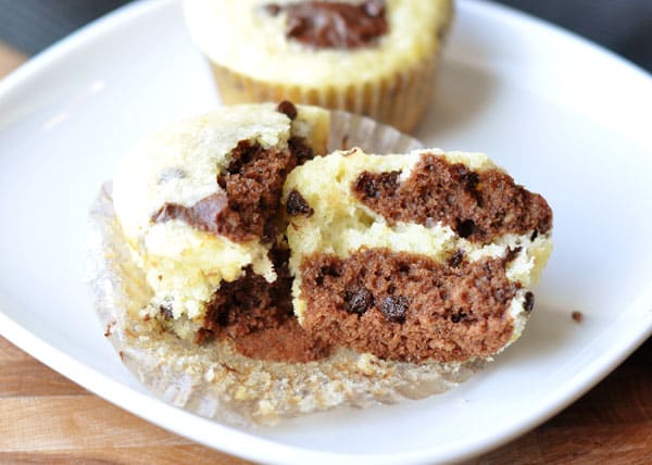 Muffin split in half with swirls of chocolate and orange batter and mini chocolate chips inside.