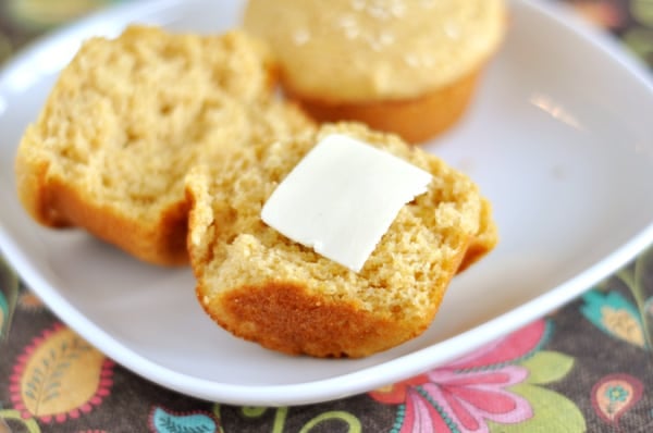 A muffin split in half with a pat of butter on one half.