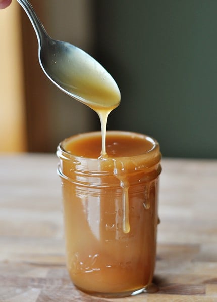 Glass jar of caramel sauce with a drip coming down the side.