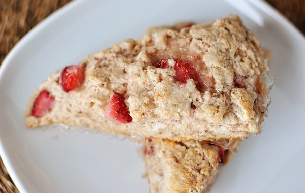 Top view of two strawberry-studded scones on a white plate.