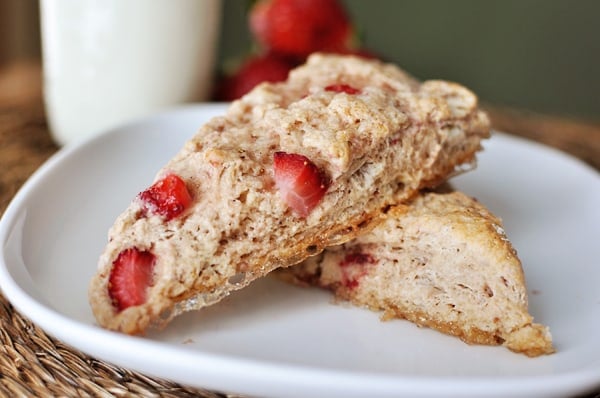 Two strawberry-studded scones stacked on top of each other on a white plate.