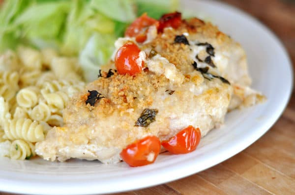 Panko crusted cooked chicken breast next to a green salad on a white plate.