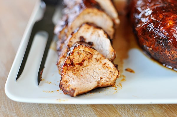 Thick slices of seasoned pork tenderloin on a white platter.